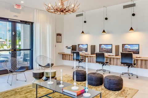 a lounge area with chairs and tables and televisions and a chandelier