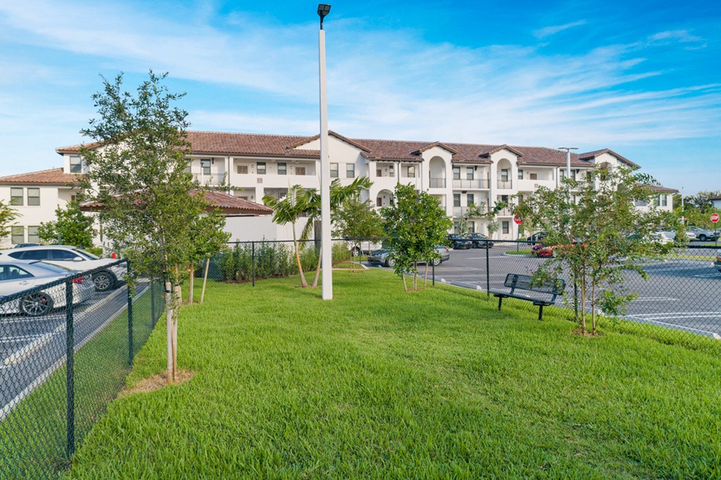 a park with grass and trees in front of a building