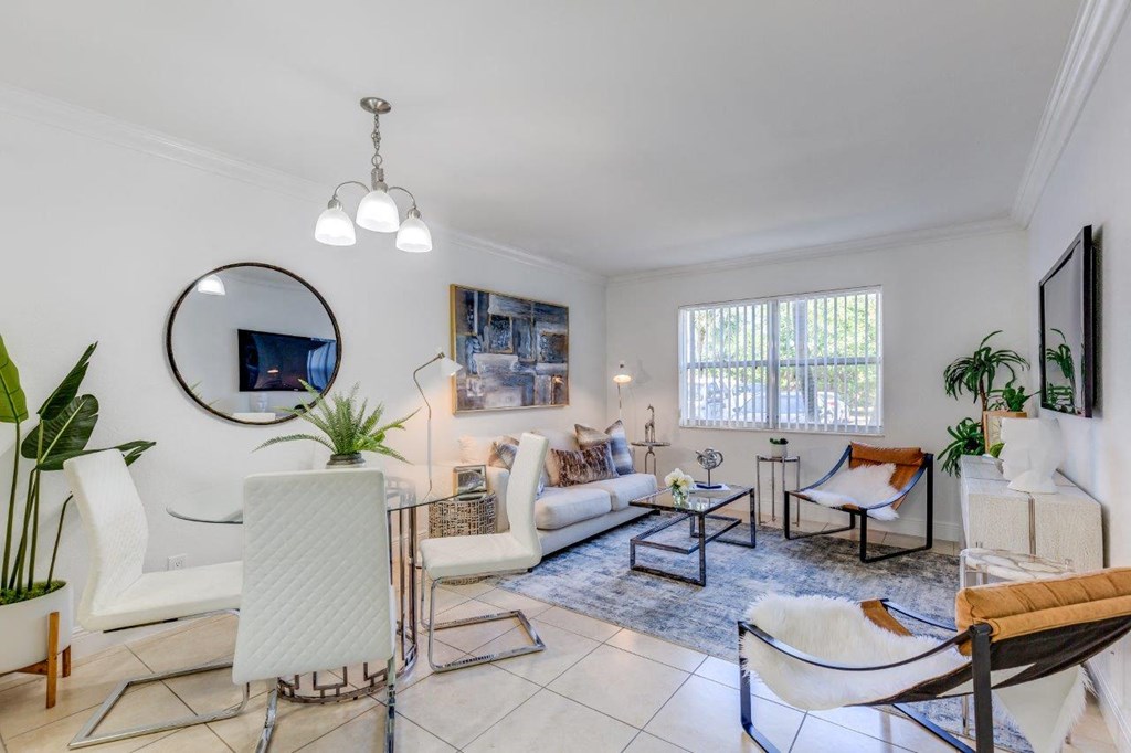 a living room with white furniture and a mirror on the wall
