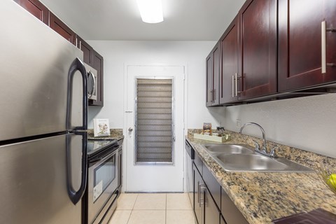 A kitchen with a stainless steel refrigerator and a granite countertop.