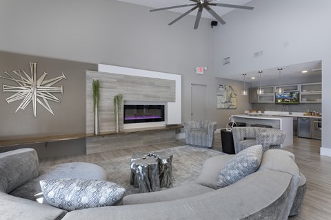 A modern living room with a grey couch and a fireplace.