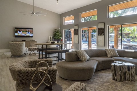 A living room with a television, couches, and a ceiling fan.