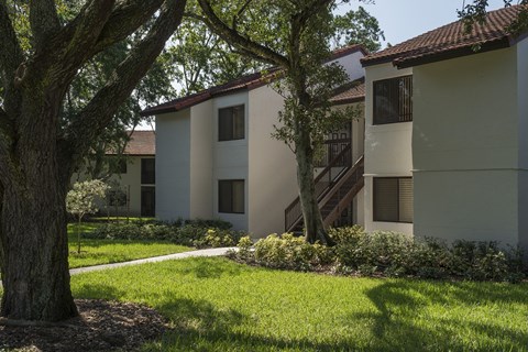 A tree in front of a building with a brown roof.