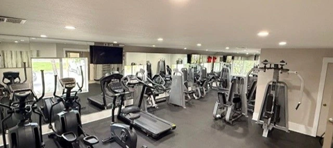 A spacious gym with a variety of equipment including treadmills, stationary bikes, and weight machines.