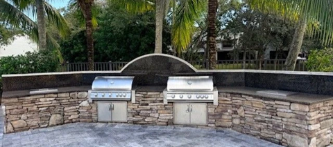 Two built-in grills are embedded in a stone wall.