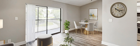 A modern dining room with a table set for two and a large clock on the wall.
