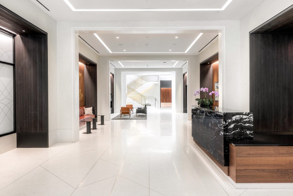 a long hallway with white tiled floors and a marble reception desk