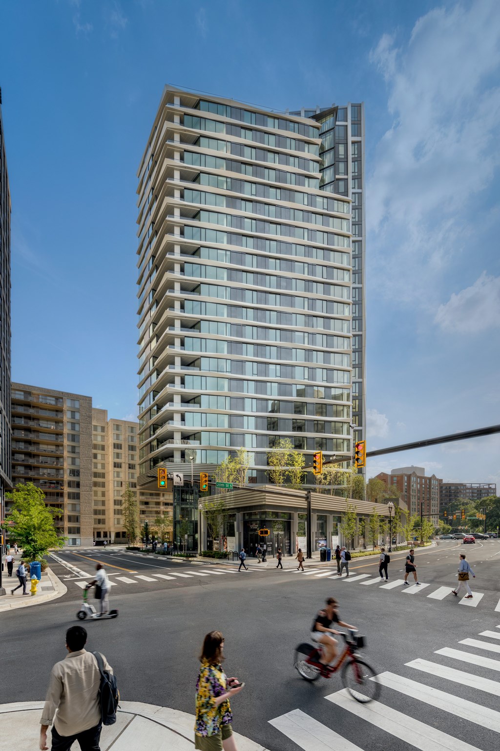 A tall building with many windows is in the middle of a city street.