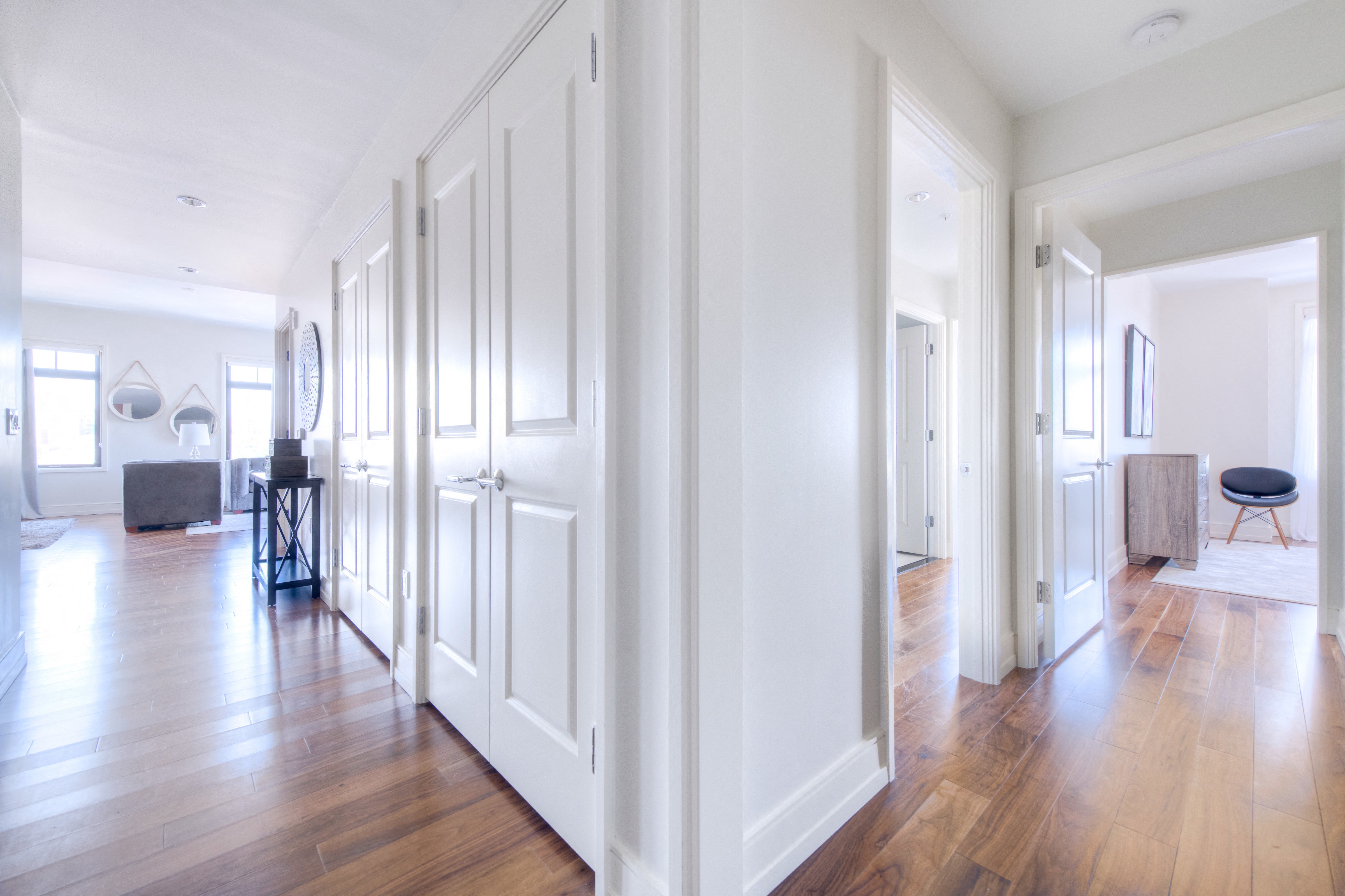 a renovated living room and hallway with white walls and wood floors