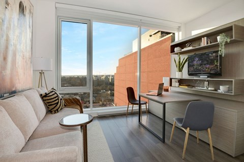 a living room with a couch and a desk and a large window