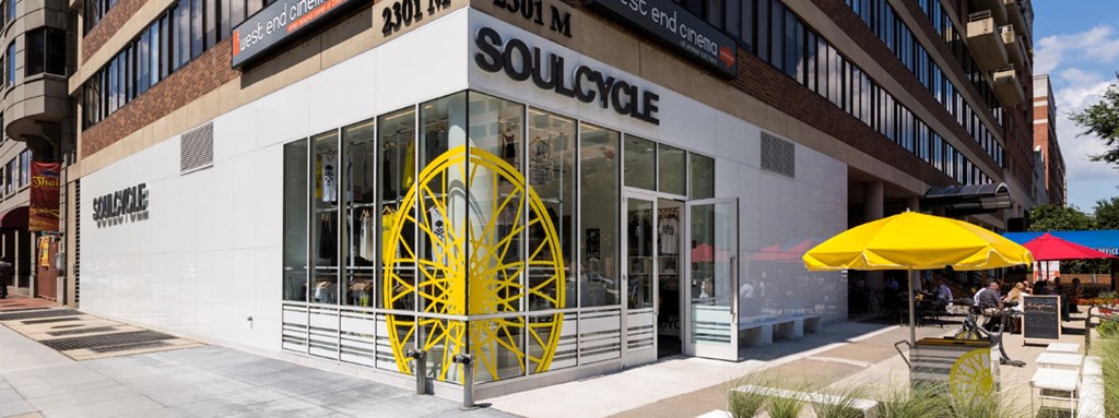 the facade of a solstice building with a yellow wheel in front of it