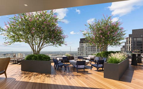 A wooden deck with a table and chairs and two flowering trees.
