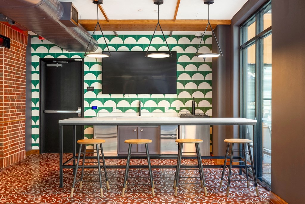 a bar with four stools in front of a green and white tile wall