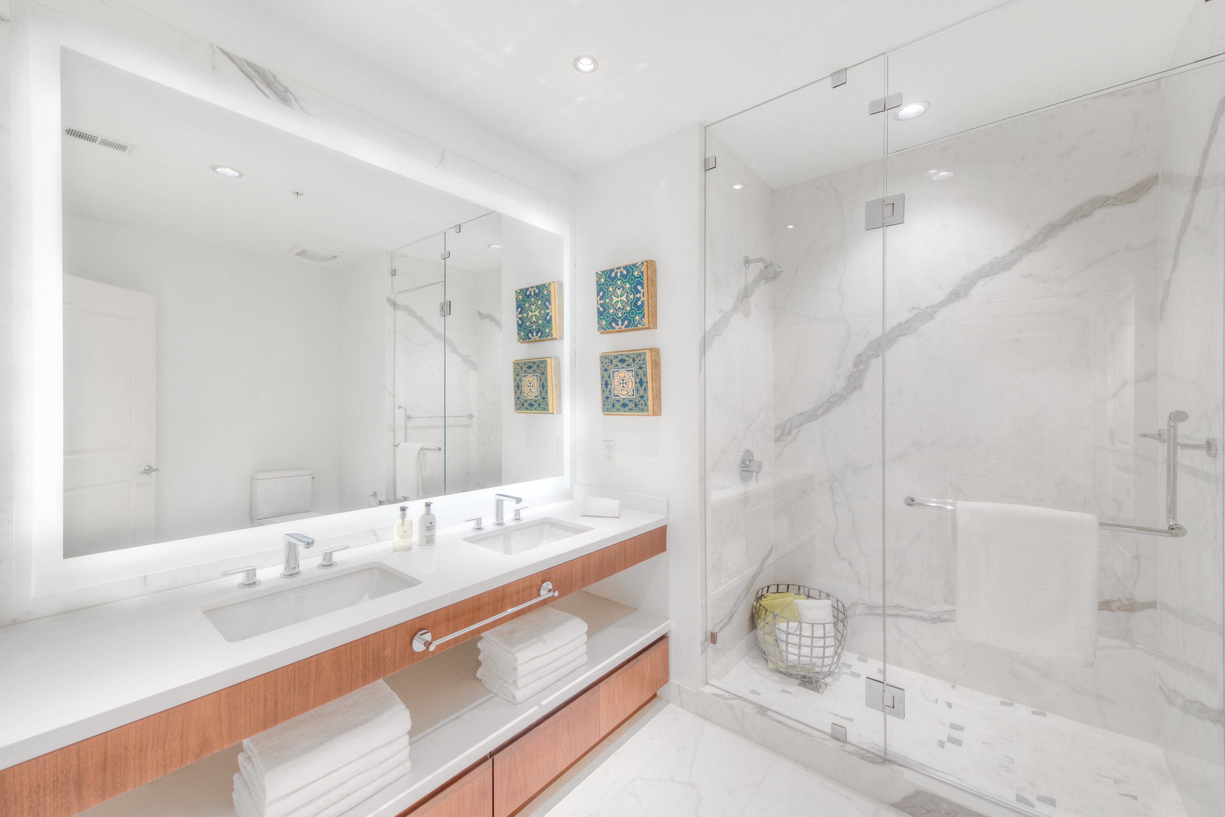 a bathroom with a large mirror and two sinks and a shower