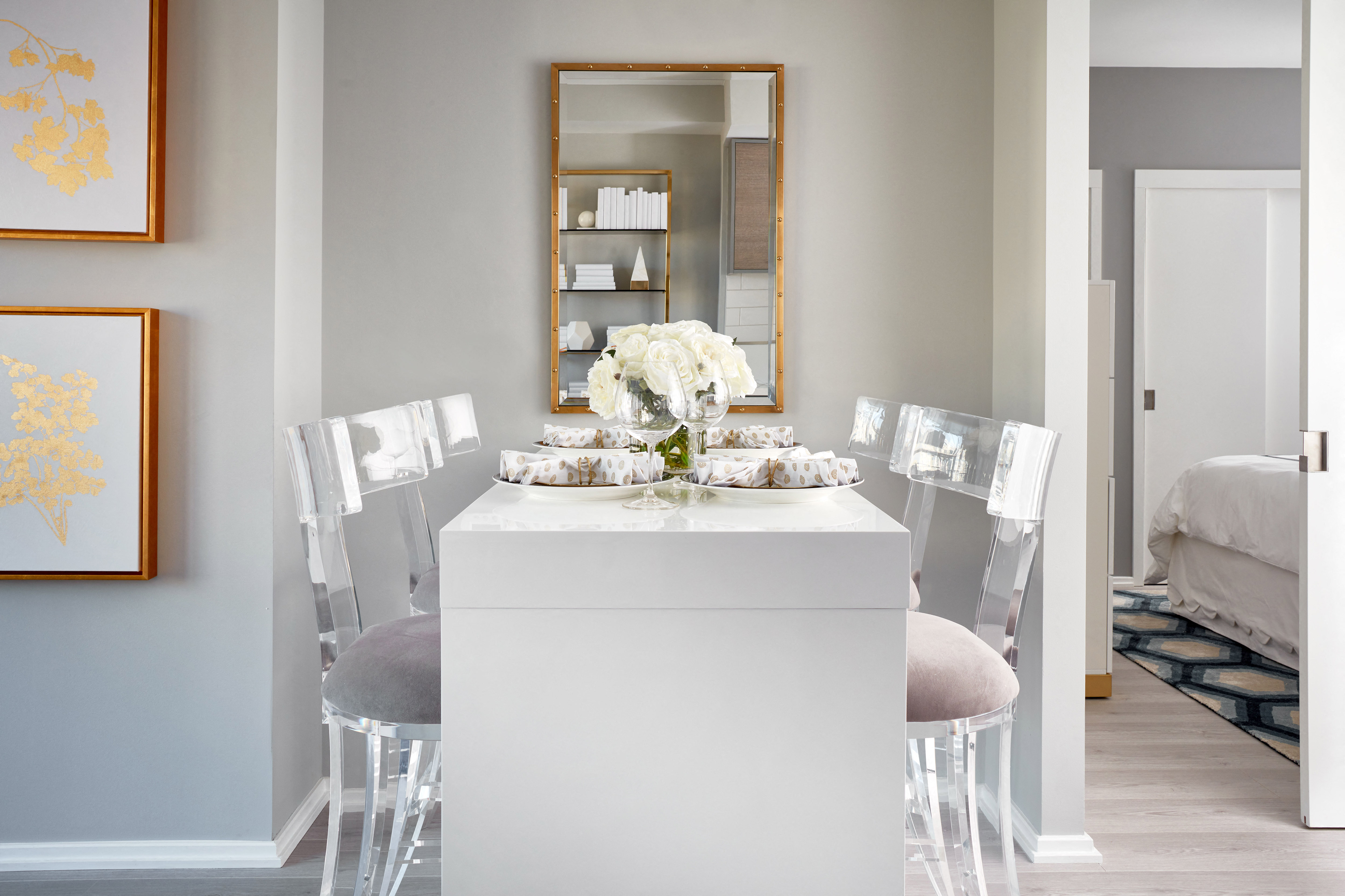 a dining room with white chairs and a white table and a mirror