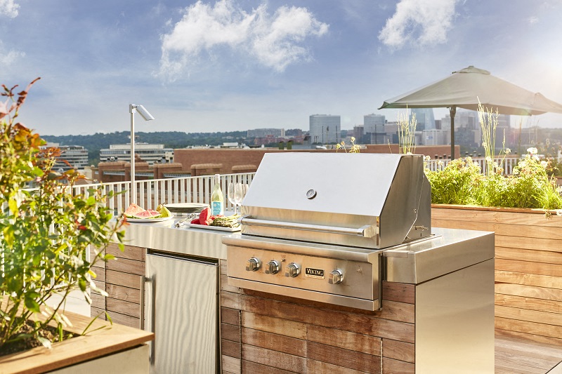 a barbecue grill on a deck with a city in the background