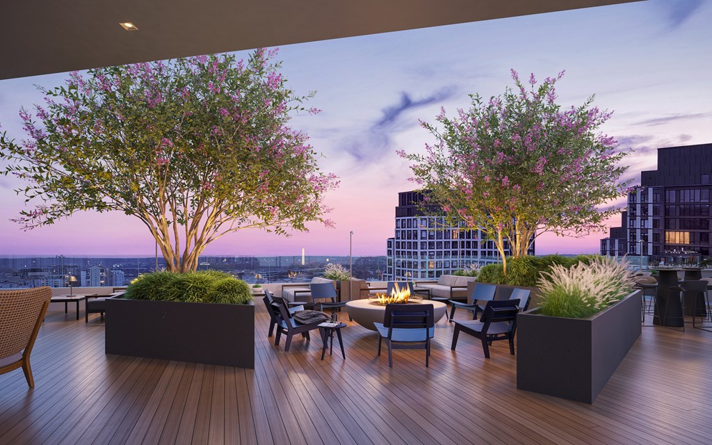 A wooden deck with a table and chairs and two trees.