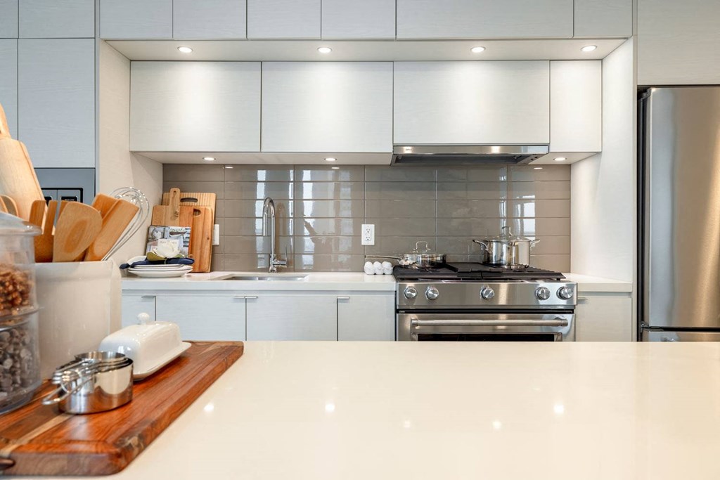 a large white kitchen with stainless steel appliances and white counter tops