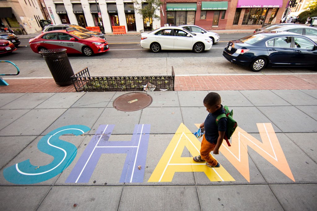 a young boy walks across a sign on the sidewalk