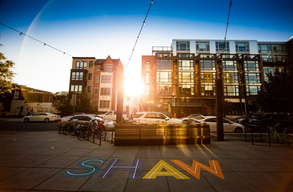 a city street with buildings and cars and a sign that reads