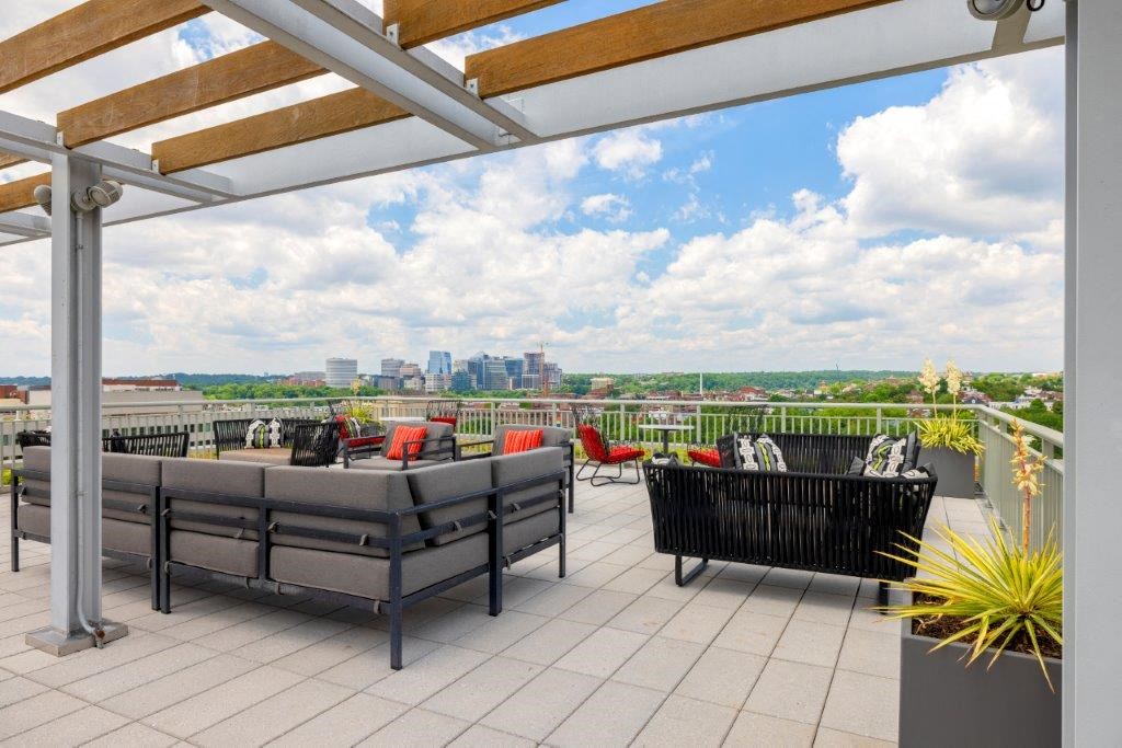 a rooftop patio with furniture and a city in the background