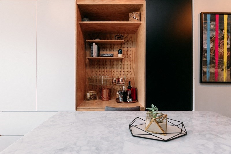 a cabinet in a kitchen with a marble counter top and a a shelf