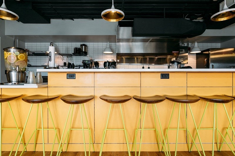 a row of yellow bar stools in front of a kitchen counter
