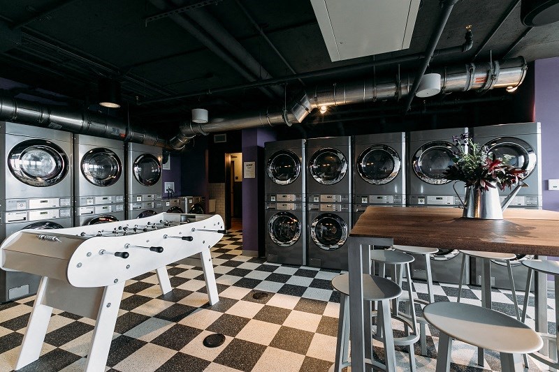 a group of washing machines in a laundry room with tables and chairs