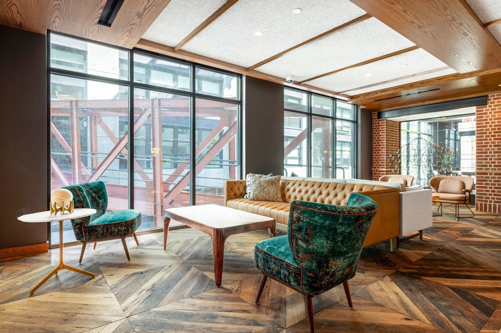 a living room with a couch and chairs and large windows