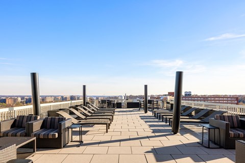 a roof top lounge area with chairs and tables and a view of the city