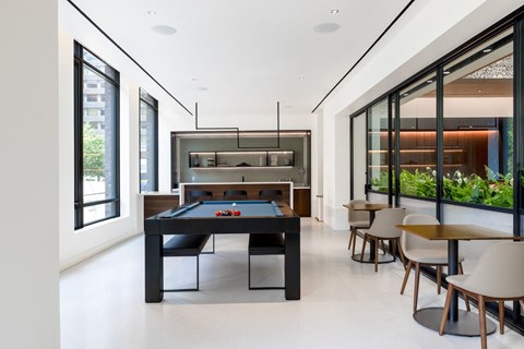 a black pool table in the center of a room with tables and chairs