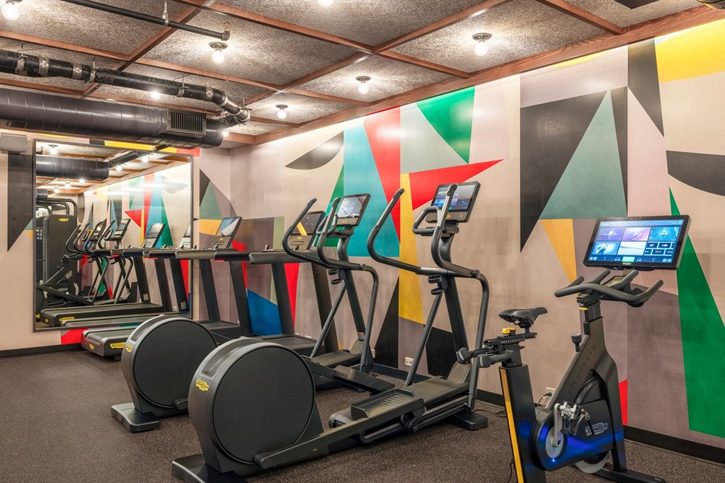 a gym with cardio equipment and a wall of colorful wallpapers