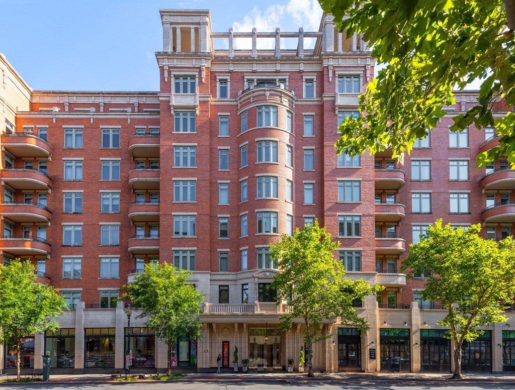 a photo of a large red brick building with balconies and trees in front of it