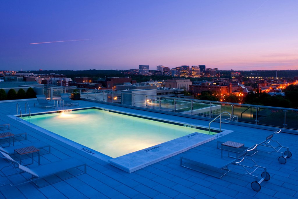 a pool on the roof of a building overlooking a city at night
