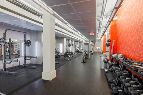 a gym with weights and a red wall and a row of pillars