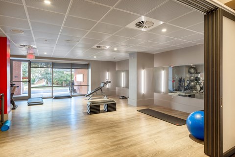 a gym with yoga mats and exercise equipment on a wooden floor
