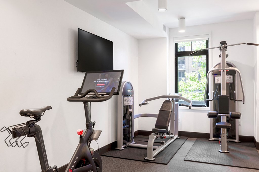 a gym with exercise equipment and a flat screen tv in a 555 waverly unit