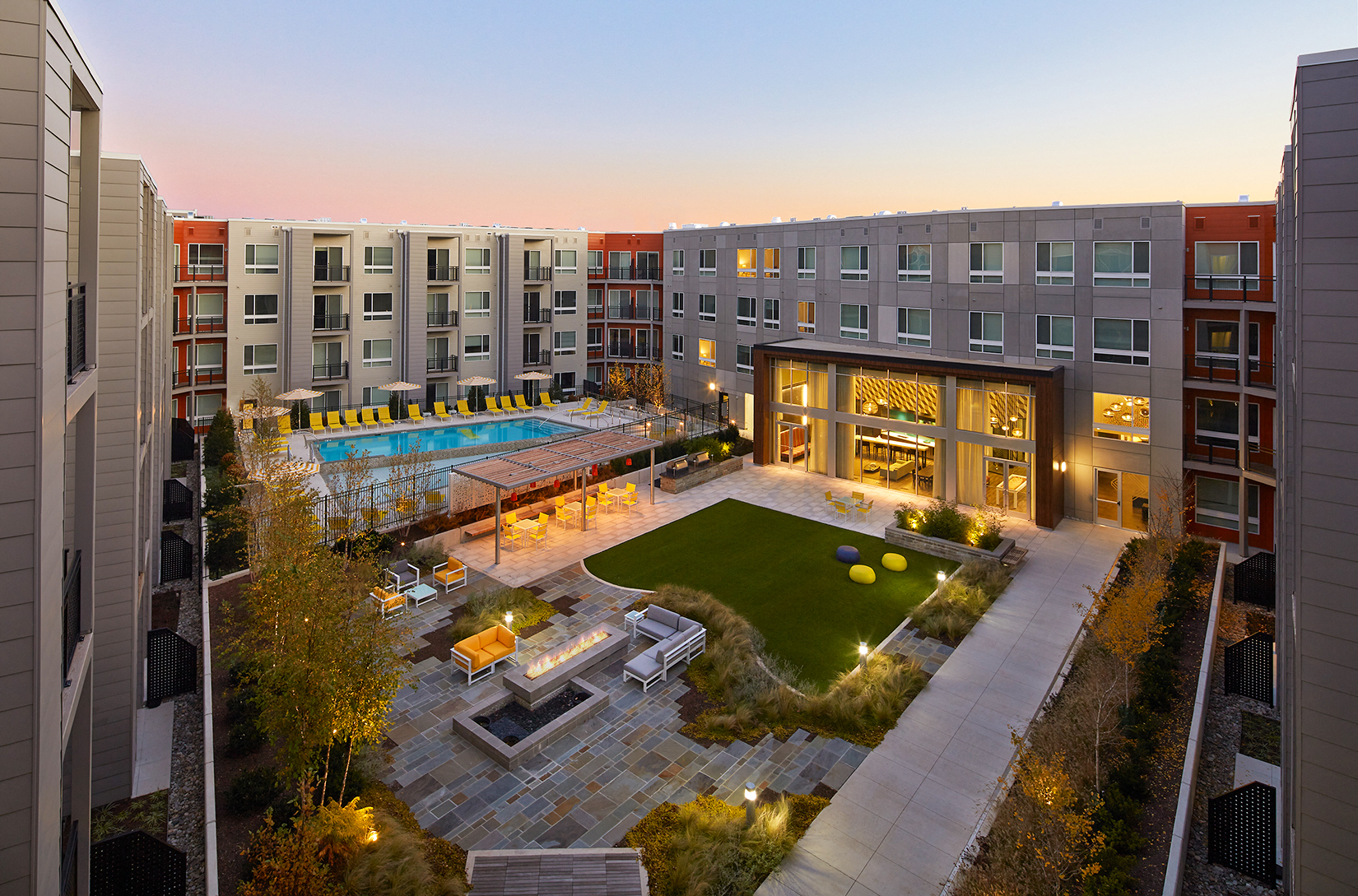 an overhead view of an apartment complex with a pool and lawn