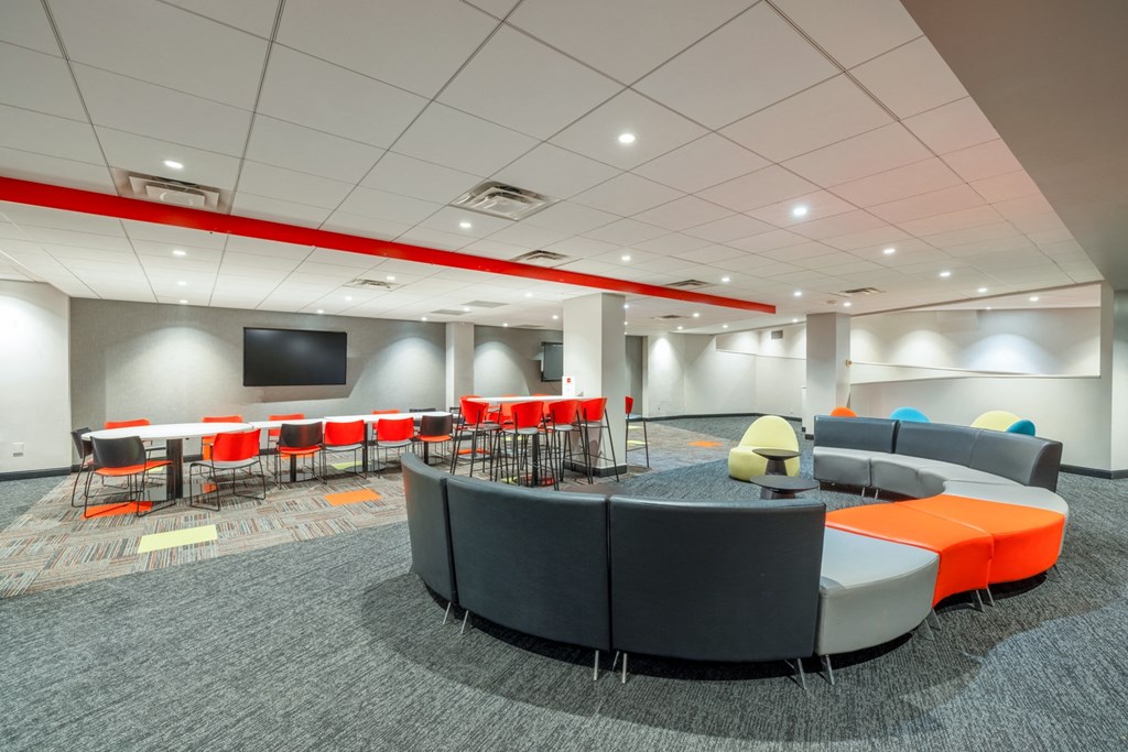 a lounge area with chairs and tables and a tv