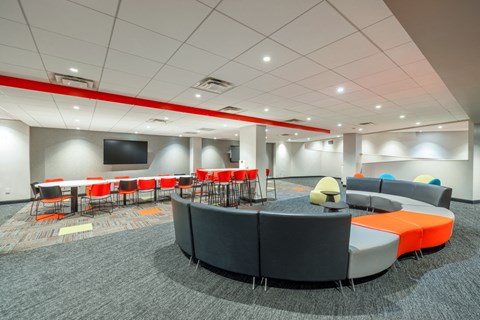 a lounge area with chairs and tables and a tv