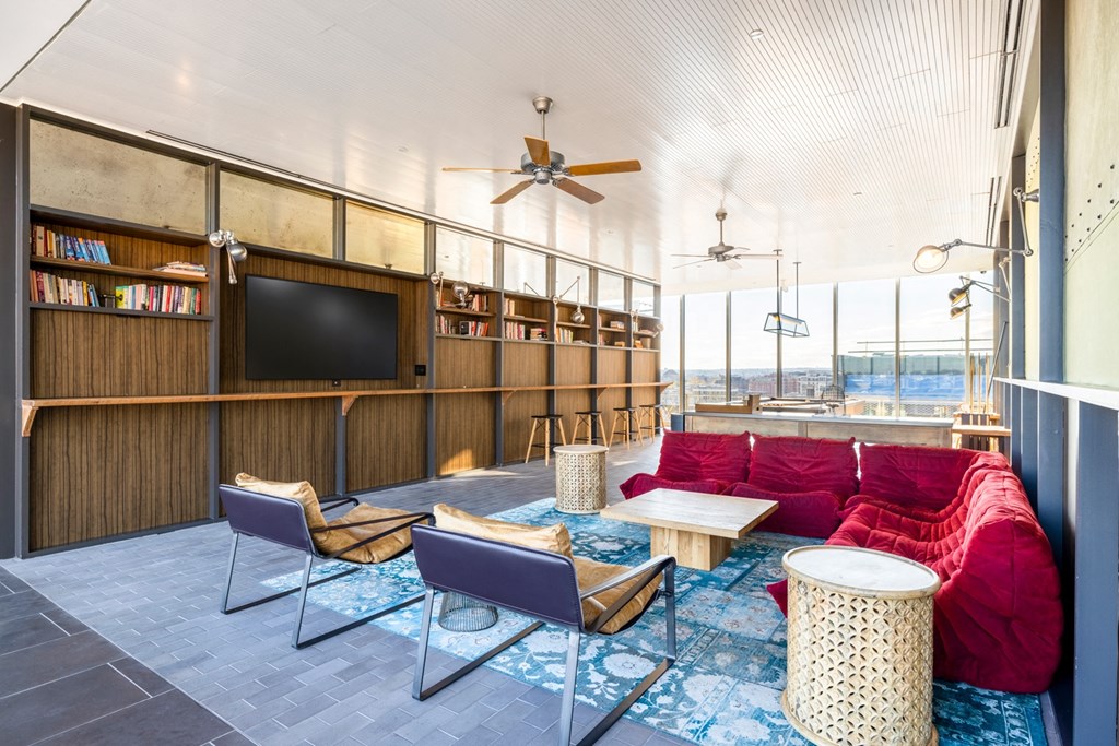 a living room with a red couch and chairs and a tv