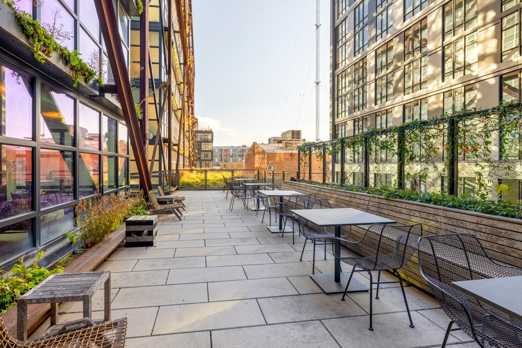 an outdoor patio with tables and chairs on a city street