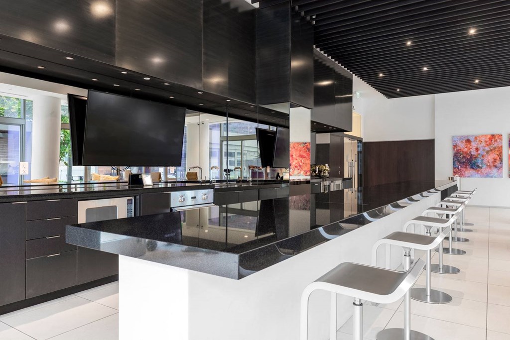 the kitchen has a bar with stools and a large tv