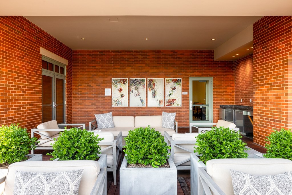 a patio with white couches and chairs and a fireplace