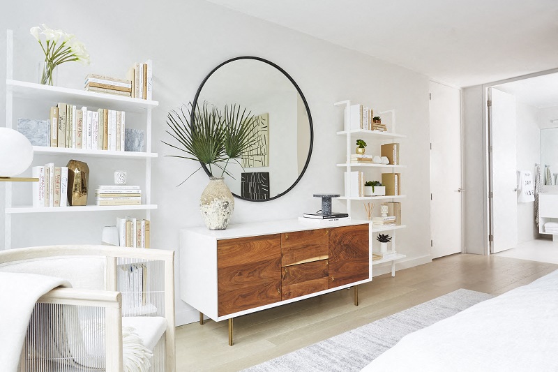 a living room with a dresser and a mirror and shelves