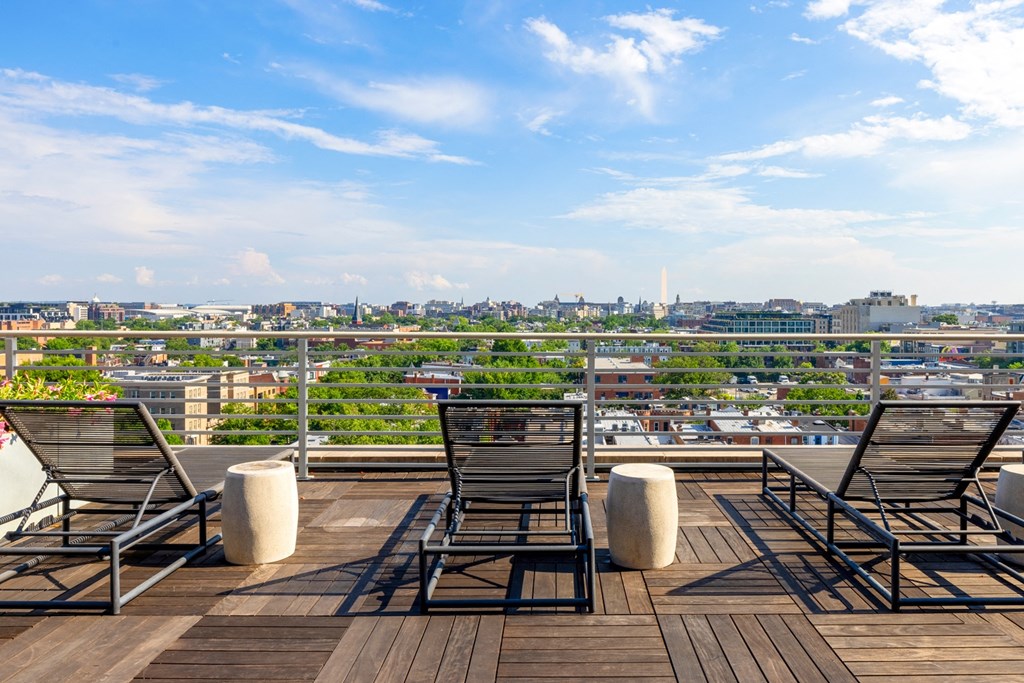 a rooftop deck with chairs and a view of the city