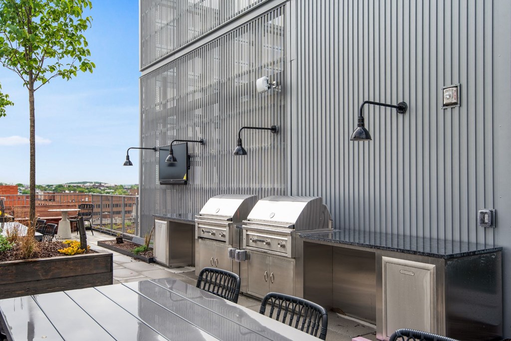 the outdoor kitchen has a grill and a table with chairs