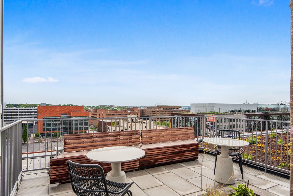 a rooftop terrace with tables and chairs and a city in the background