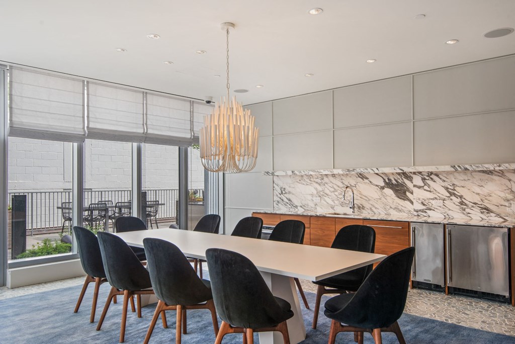 a dining room with a white table and chairs and a kitchen with a marble counter