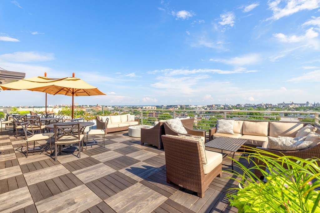 an outdoor patio with couches and tables with umbrellas and a view of the city